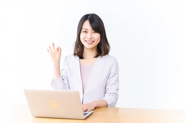 パソコンの前で女性がOKしている写真